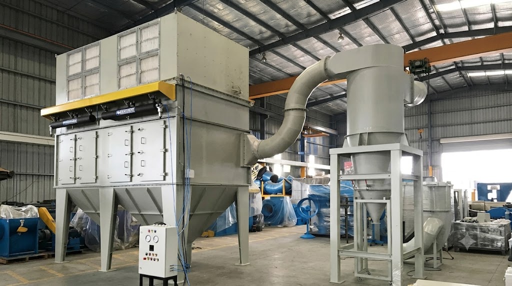 Industrial dust collector and cyclone separator system installed inside a manufacturing warehouse facility for air pollution control.